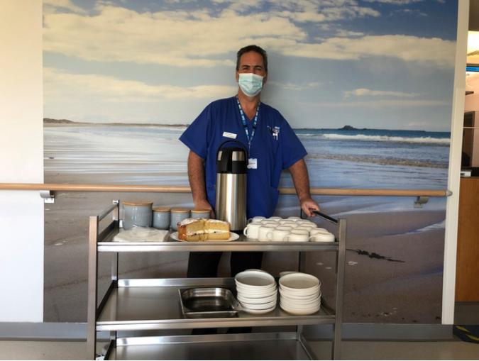 Nurse with hostess trolley displaying drinks and cakes