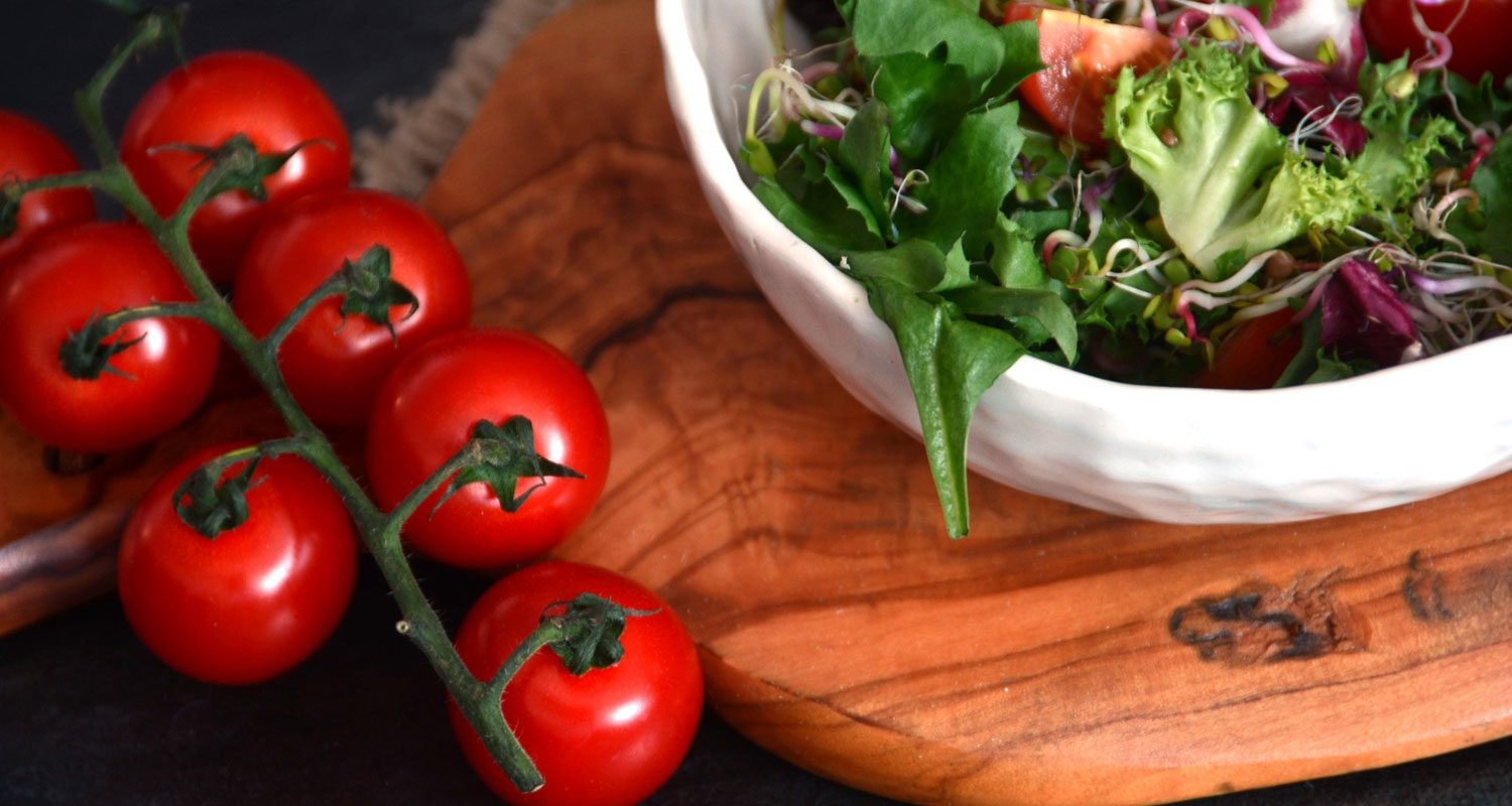  Image of salad in a bowl and tomatoes to the side on a chopping board